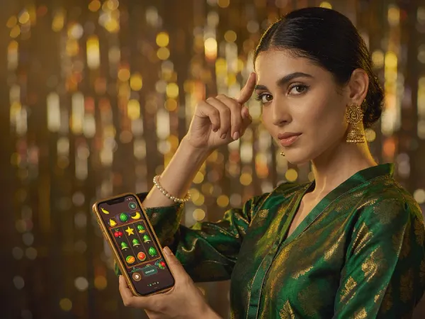 p88 Woman in an emerald and gold kameez holding a phone with a glowing slot game