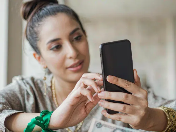 p88 Hands holding a smartphone with an abstract payment screen above a wooden table