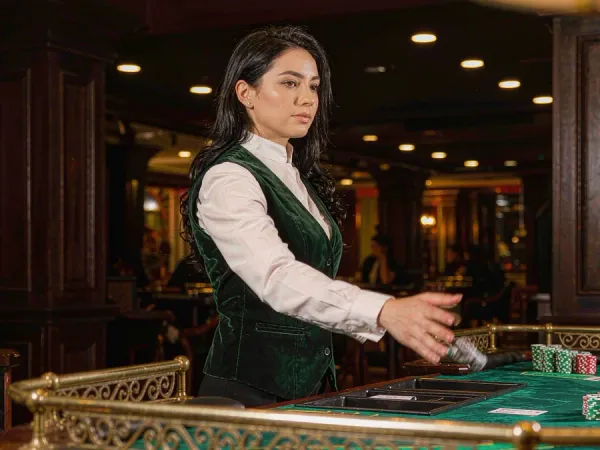 p88 Dealer revealing cards at a baccarat table with neat chip stacks